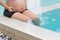 Pregnant woman hands holding belly on swimming pool.