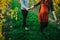 pregnant woman and her husband hand by hand in vineyards