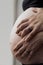 Pregnant woman with her husband hands around her belly