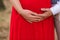 Pregnant woman and her husband holding hand on baby bump. Close up of multiethnic couple. Loving future couple expecting