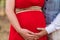 Pregnant woman and her husband holding hand on baby bump. Close up of multiethnic couple. Loving future couple expecting