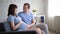 Pregnant woman and her husband sitting on a sofa, talking and touching tummy