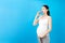 Pregnant woman holding asthma inhaler to prevent attack at colorful background with copy space. Future mother is suffering