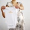Pregnant woman holding baby clothing with & x27;100% natural& x27; word on it. Conceptual image shot