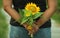 Pregnant woman holding flowers in the back. Sunflowers bouquet in hand