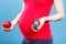 Pregnant woman holding fresh apple and glucometer with good result sugar level, diabetes during pregnancy