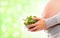 A pregnant woman holding a fresh green salad