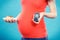 Pregnant woman holding glucose meter with good result sugar level and piece of cheesecake, diabetes and nutrition during pregnancy