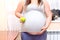 Pregnant woman holding a green apple in his hand next to the belly. Diet for pregnant women.