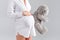 Pregnant woman holding soft toy. Pretty young woman carrying teddy bear.