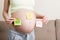 Pregnant woman holding square multicolored stickers with question marks
