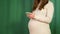 A pregnant woman holds the phone and calls the doctor, watches the news. Pregnancy and motherhood concept. Close-up of a
