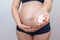 Pregnant woman holds pills in the palm of her hand against the background of her stomach