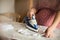 Pregnant woman ironing baby laundry at home