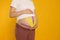 Pregnant woman with kinesio tapes on her belly against orange background, closeup. Space for text