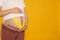 Pregnant woman with kinesio tapes on her belly against orange background, closeup. Space for text