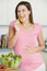 Pregnant woman in kitchen making a salad