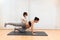 A pregnant woman kneeling on mat doing pilates on a mat with help of physiotherapist with copy space