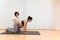 A pregnant woman kneeling on a mat doing yoga with help of physiotherapist in spa center