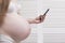 Pregnant woman in lingerie enjoys a smartphone. Call an ambulance. Prenatal contractions