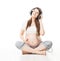 Pregnant woman listening to music in headphones and relaxing over white background