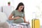 Pregnant woman making list while packing suitcase for maternity hospital