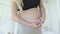 Pregnant woman measuring belly and smiling at camera. Happy smiling Caucasian expectant awaiting for baby. Beautiful