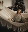 Pregnant woman meditates in hammock against background of Christmas tree