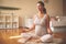 Pregnant woman meditates indoor in yoga pose. Woman enjoying in