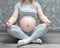Pregnant woman meditating at home, practicing yoga. Young happy expectant relaxing
