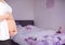 Pregnant woman mid section holding stomach in blurry bedroom with pink overlay