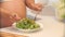 Pregnant woman mixing salad in a bowl in the kitchen.