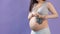 Pregnant woman mother holding grey baby shoes with belly exposed