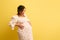 Pregnant woman, mother to-be holds belly, cries and shouts, isolated on yellow. Easy delivery, pregnancy and parturition