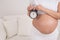 A pregnant woman with a naked belly holds an alarm clock. Intended date of birth.