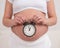 A pregnant woman with a naked belly holds an alarm clock. Intended date of birth.