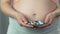 Pregnant woman putting up bowl with pills, making refusal gesture, no medication