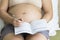 Pregnant woman record in note book in bedroom.