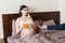 Pregnant woman relaxing in bed is eating chocolate cereal balls and drinking juice. Husband is feeding his wife. Dry breakfast