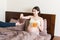 Pregnant woman relaxing in bed is eating chocolate cereal balls and drinking juice. Husband is feeding his wife. Dry breakfast