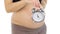 Pregnant woman\'s belly with an alarm clock, white, closeup