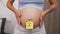 pregnant woman's belly with a sticky note saying boy, closeup gender reveal concept