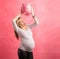 Pregnant woman in shock shaking piggy bank