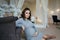 Pregnant woman sit near the armchair. Beautiful woman waiting for a baby. Elegant pregnant model at home