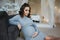 Pregnant woman sit near the armchair. Beautiful woman waiting for a baby. Elegant pregnant model at home