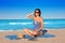 Pregnant woman sitting on blue beach sand