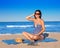 Pregnant woman sitting on blue beach sand