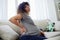 Pregnant woman sitting on the couch lower back pain and headache, strain on the spine during pregnancy. Lifestyle