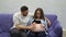 Pregnant woman sitting at home on the couch with her husband watching television. A man communicates with his wife and