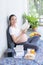 A pregnant woman sitting in the morning light reading a book in the living room